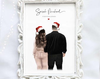 Op de afbeelding: Een ingelijste print met een stel dat van achteren te zien is en kerstmutsen draagt. De print bevat de namen "Sarah Michael" en de tekst "Forever & Always" in sierlijke letters, met een rood hart. De lijst is wit.