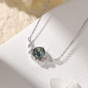 May include: A silver necklace featuring a green and white agate stone pendant. The pendant is surrounded by a delicate silver branch design.