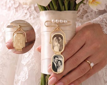 May include: A gold-toned metal locket pin featuring a vertical double-frame design. The locket displays two black and white photographs of a couple. The pin is adorned with four small white pearls and is attached to a cream-colored satin ribbon wrap.