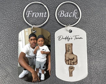 May include: A silver keychain with two tags. The front tag features a photo of a father and son. The back tag has a drawing of two fists bumping, with the words "Daddy's Team" above the fists.
