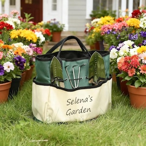 Pu&ograve; includere: Una borsa da giardinaggio verde e crema con manici e finiture nere, contenente due cazzuole e un coltivatore a tre punte. La borsa &egrave; personalizzata con "Selena's Garden" in corsivo nero. La borsa &egrave; appoggiata sull'erba, circondata da fiori in vaso.