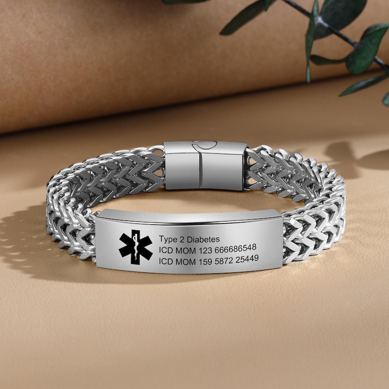 May include: Silver medical ID bracelet with a black star of life symbol and engraved text: "Type 2 Diabetes, ICD MOM 123 666686548, ICD MOM 159 5872 25449".
