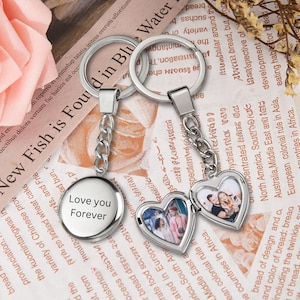 May include: A silver keychain with two charms. One charm is a round disc with the text "Love you Forever". The other charm is a heart-shaped locket with a photo of a group of people inside.