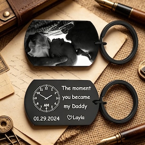 Może przedstawiać: Czarne breloczki do kluczy. Jeden z nich zawiera czarno-białe zdjęcie, drugi tekst "The moment you became my Daddy", datę 01.29.2024 i imię "Layla".