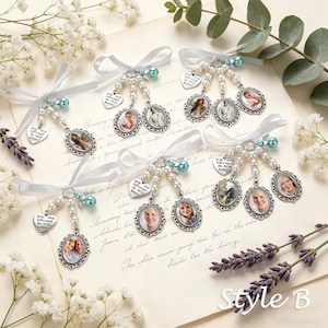 May include: Five silver-toned photo charms featuring oval frames with portraits, white ribbon bows, pearl-like beads, teal accent beads, and heart-shaped metal tags engraved with the text You are always in my heart, arranged on a paper background.