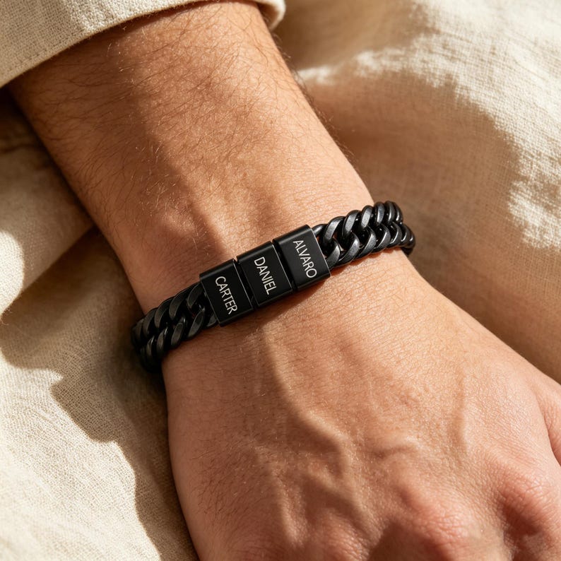 Puede incluir: Una pulsera de cadena de eslabones negros mate con tres cuentas rectangulares. Cada cuenta est&aacute; grabada con un nombre en letras may&uacute;sculas blancas, que dicen Carter, Daniel y Alvaro. La pulsera cuenta con un mecanismo de cierre seguro.