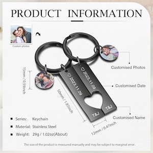 May include: A black metal keychain with two heart-shaped charms. The charms are engraved with a date and the initials "T&J". The keychain also has two small round charms that can be customized with photos. The keychain is 5 cm long and 1.5 cm wide.