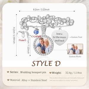May include: A silver-toned wedding bouquet pin measuring 3.23 inches by 2.44 inches. It features a floral design with clear stones, a circular photo frame, a heart-shaped charm engraved with 'love u to the moon and back', and a blue crystal bead.