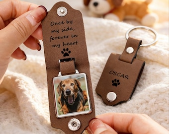 May include: Brown leather keychain with a photo of a dog and the text "Once by my side, forever in my heart." A second keychain has the name "OSCAR" and a paw print. A stuffed dog is in the background.