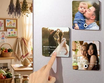 May include: Three square photo magnets attached to a refrigerator. Each magnet displays a custom photograph with a music player interface overlay, including song titles like Because You Live, play buttons, and progress bars for a personalized look.