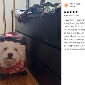 May include: A rolling suitcase with a gold handle and a large image of a white dog with a red bandana. The suitcase is black and has a tag on top. The size is 18-20 inches.