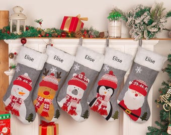 May include: Five gray Christmas stockings with white faux fur cuffs are displayed. Each stocking features a different festive character: a snowman, reindeer, polar bear, penguin, and Santa Claus. The name "Elise" is embroidered on each stocking.
