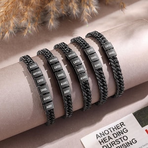Puede incluir: Cinco pulseras de eslabones de metal negro, cada una con m&uacute;ltiples segmentos rectangulares grabados con nombres como Jackson, Matthew, Carter, Daniel, Alvaro y Avery. Las pulseras tienen un acabado mate oscuro y un dise&ntilde;o entrelazado.
