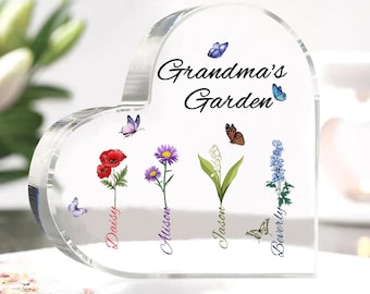May include: A clear heart-shaped crystal paperweight with the text "Grandma's Garden" at the top.  Four flowers with butterflies and names are displayed below: Daisy, Allison, Jason, and Beverly.