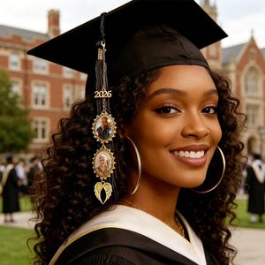 Puede incluir: Una persona sonriente con un birrete negro con borla y adornos dorados. Los adornos incluyen el año 2026, dos marcos de fotos ovalados y un par de alas de ángel. La persona lleva una toga negra y pendientes de aro dorados grandes.