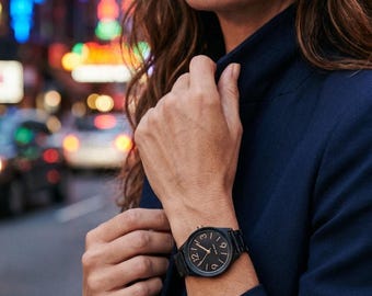 Reloj Nine West con correa de caucho negro y detalles dorados. Batería nueva.