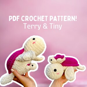 May include: PDF crochet pattern for Terry & Tiny, two crocheted plush sea turtles. The larger turtle is white with a pink shell and the smaller turtle is white with a pink shell and a pink flower on its head.