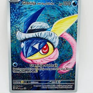 May include: A Pokemon trading card featuring Greninja wearing a grey felt hat. The card has a blue and white background with the text "Greninja with Grey Felt Hat" and "Greninja-Portrait". The card also includes game instructions and stats.