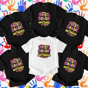 May include: Black and white t-shirts with the text "FIRST GRADE" in a colorful, bubble-style font. The shirts are personalized with the names "Mr. Smith" and "Mrs. Jones". The background features colorful handprints.