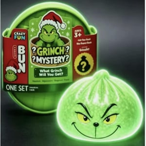 May include: A round green Grinch Mystery Bun toy in a circular container. The packaging features the text Crazy Fun, Grinch Mystery, What Grinch Will You Get, and Ages 3+. The toy is a light green, glowing, rounded bun with a printed Grinch face.