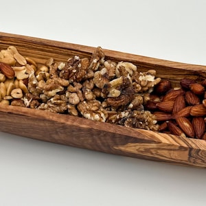 May include: A wooden serving bowl with three compartments filled with almonds, walnuts, and peanuts. The bowl is made of olive wood and has a natural brown colour.