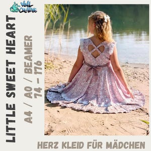 May include: A dusty pink dress with a white floral pattern, featuring a heart-shaped cutout on the back, ruffled sleeves, and a tied waist sash. The text on the side reads LITTLE SWEET HEART, A4 / A0 / BEAMER, 74 - 176, and HERZ KLEID FÜR MÄDCHEN.