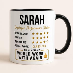 May include: A white ceramic mug with a black handle and interior. The front features the name SARAH in bold black text above the heading Employee Performance Review. It lists categories with gold star ratings and the text WOULD WORK WITH AGAIN.
