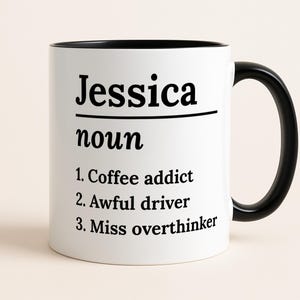 May include: A white ceramic mug with a black interior and handle. The mug displays the name "Jessica" above "noun" and three definitions: "Coffee addict," "Awful driver," and "Miss overthinker."
