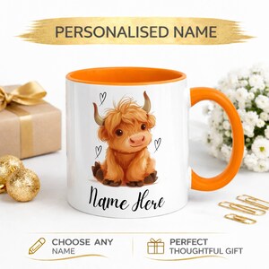 Pode incluir: Caneca de cer&acirc;mica branca com interior e al&ccedil;a laranja. A caneca apresenta uma ilustra&ccedil;&atilde;o de vaca Highland com cora&ccedil;&otilde;es e o texto "Name Here". O banner superior diz "PERSONALISED NAME".