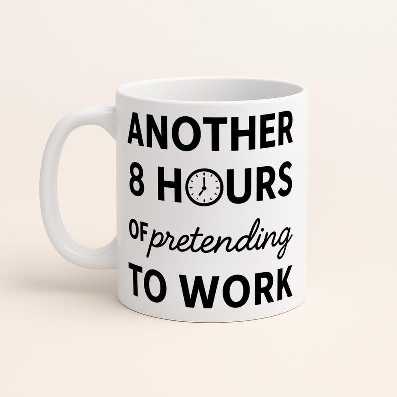 K&ouml;nnte beinhalten: Wei&szlig;e Keramik-Tasse mit schwarzem Henkel. Die Tasse zeigt den Text "ANOTHER 8 HOURS of pretending TO WORK" in schwarzer, fetter Schrift. Eine Uhrgrafik befindet sich zwischen "8 HOURS".
