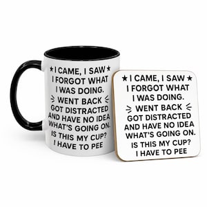 K&ouml;nnte beinhalten: Eine wei&szlig;e Keramiktasse mit schwarzem Henkel und Rand sowie ein passender Untersetzer. Beide Artikel zeigen den Text "I CAME, I SAW, I FORGOT WHAT I WAS DOING" in Schwarz, mit einer Stern-Grafik.