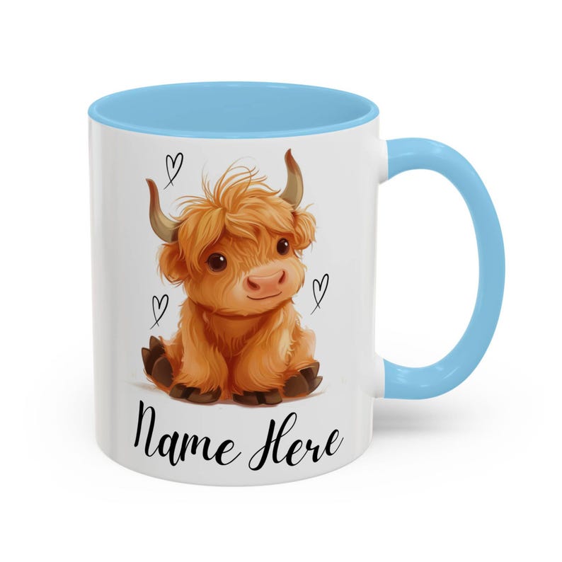 Pode incluir: Caneca de cer&acirc;mica branca com interior e al&ccedil;a azul claro. A caneca apresenta uma ilustra&ccedil;&atilde;o de desenho animado de uma vaca Highland com p&ecirc;lo castanho, pequenos chifres e tr&ecirc;s cora&ccedil;&otilde;es pretos. O texto "Name Here" est&aacute; escrito em preto.