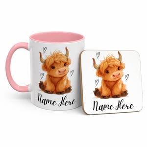 Pode incluir: Uma caneca de cer&acirc;mica branca com interior e al&ccedil;a rosa, e um porta-copos quadrado a condizer. Ambos apresentam uma ilustra&ccedil;&atilde;o de desenho animado de uma vaca das Terras Altas com o texto "Name Here" e pequenos rabiscos de cora&ccedil;&atilde;o. A vaca &eacute; castanha com pequenos chifres.