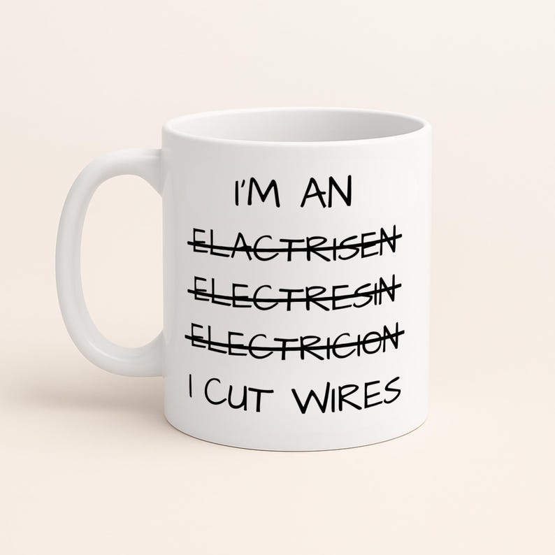May include: A white ceramic mug featuring black text that reads I'M AN, followed by three crossed-out misspelled attempts at the word electrician, and finally the phrase I CUT WIRES. The mug has a standard handle and a smooth cylindrical body.