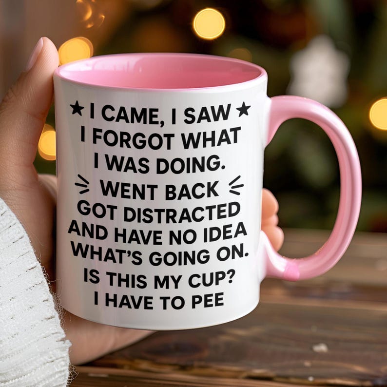 K&ouml;nnte beinhalten: Wei&szlig;er Keramikbecher mit rosa Innenraum und Henkel. Der Becher zeigt den Text "I CAME, I SAW, I FORGOT WHAT I WAS DOING. WENT BACK, GOT DISTRACTED AND HAVE NO IDEA WHAT'S GOING ON. IS THIS MY CUP? I HAVE TO PEE."