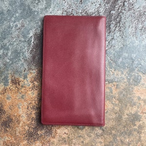 May include: A burgundy leather wallet with a stitched edge.