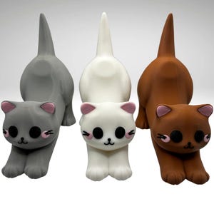 May include: Four cat figurines in grey, white, and brown. Each cat has a pink-accented face, black eyes, and a tail pointing upwards. The cats are in a playful pose, with their front paws extended.