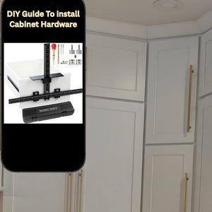 May include: A smartphone screen displays "DIY Guide To Install Cabinet Hardware." The image shows a cabinet hardware installation kit, including a black jig, drill bits, and a case. White cabinets with gold handles are in the background.