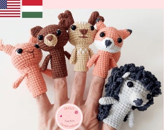 May include: Crochet pattern featuring five handmade finger puppets: a pink pig, a brown bear, a tan deer, an orange fox, and a gray poodle. The puppets are displayed on fingers. The text "CROCHET PATTERN" is at the top.