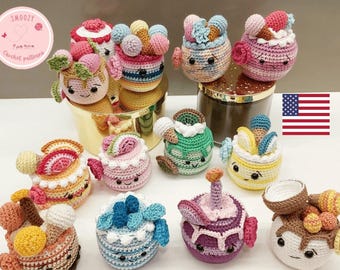 May include: A collection of 10 colorful crocheted amigurumi cake toys. Each cake has a different design and features a cute face. The cakes are arranged on a gold surface with a glass jar and a US flag in the background. Download pdf-pattern.