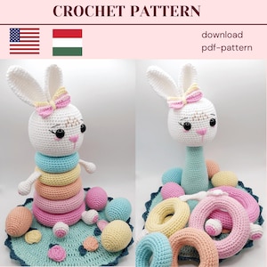 Può includere: Un coniglio bianco all'uncinetto con accenti rosa e gialli, che tiene un mucchio di anelli colorati. Il coniglio è seduto su un tappetino all'uncinetto blu e verde con anelli e palline aggiuntive.