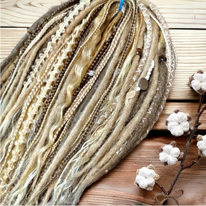 May include: A set of brown, blonde, and white synthetic dreadlocks with beads and charms. The dreadlocks are arranged in a fan shape and are lying on a wooden surface.