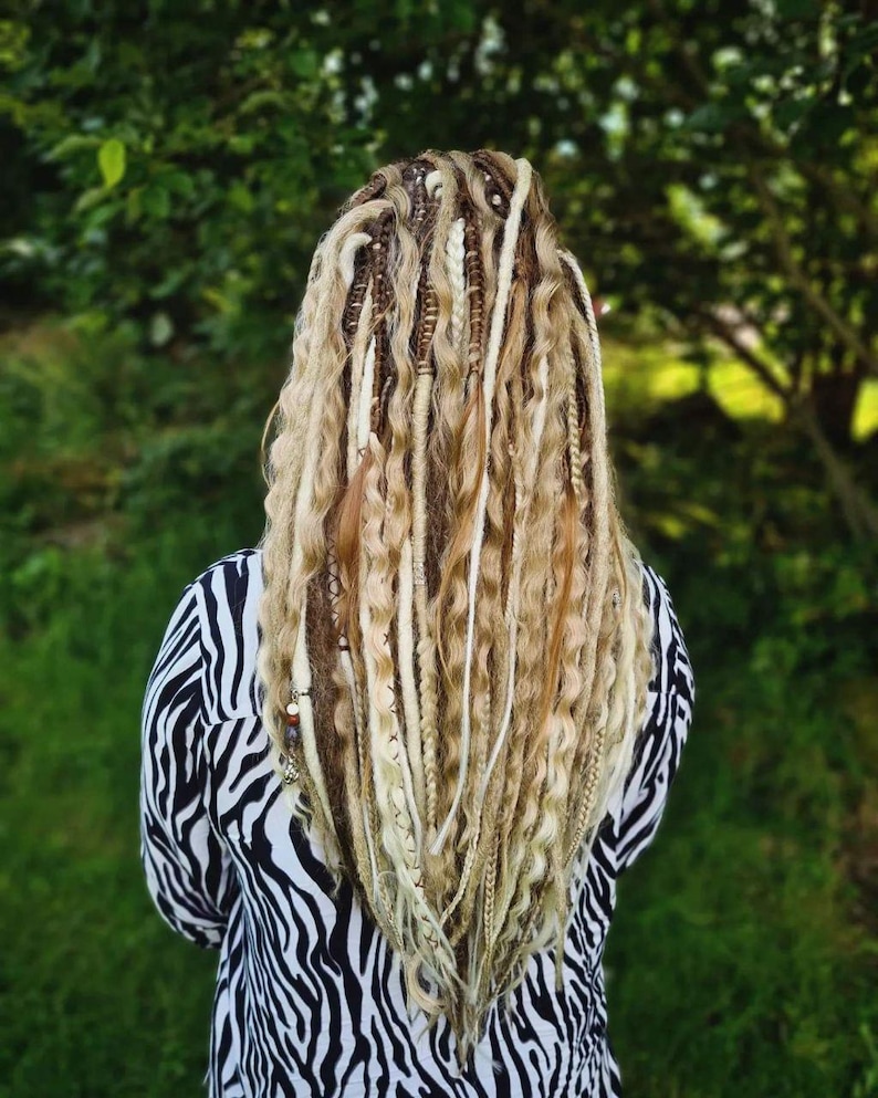May include: A person with long, blonde dreadlocks with brown and white accents. The dreadlocks are styled in a wavy pattern and fall to the person's waist.
