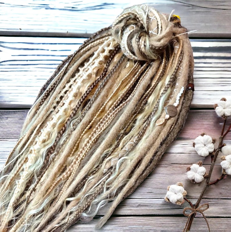 May include: A set of brown, blonde, and white synthetic dreadlocks with a variety of textures, including wavy, straight, and braided. The dreadlocks are tied together with a brown string and have beads and charms.