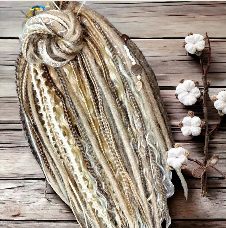 May include: A set of brown, blonde, and white synthetic hair extensions with a braided knot at the top. The extensions are arranged in a fan shape and have a natural, wavy texture.