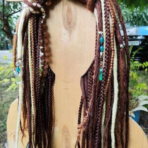 K&ouml;nnte beinhalten: Braune, beige und wei&szlig;e synthetische Dreadlocks mit t&uuml;rkisfarbenen und silbernen Perlen. Die Dreadlocks sind oben mit einer braunen Schnur zusammengebunden.