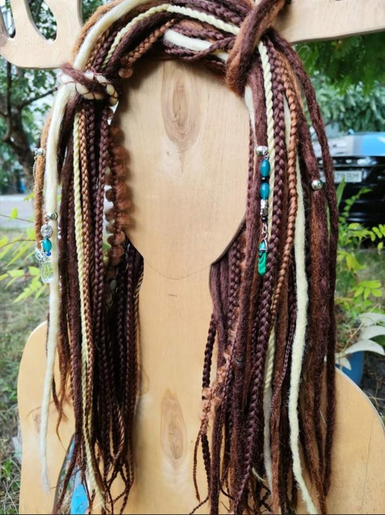 K&ouml;nnte beinhalten: Braune, beige und wei&szlig;e synthetische Dreadlocks mit t&uuml;rkisfarbenen und silbernen Perlen. Die Dreadlocks sind oben mit einer braunen Schnur zusammengebunden.