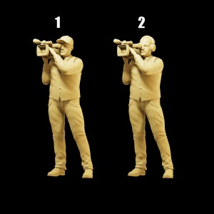 May include: Two figures in a studio setting, both wearing a vest and holding a video camera. The figure on the left is wearing a baseball cap, while the figure on the right is wearing headphones. The background is black.