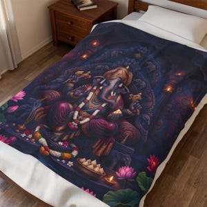 Könnte beinhalten: Eine weiche Wohndecke mit einer detaillierten Illustration der Gottheit Ganesha in tiefen Violett-, Blau- und Goldtönen. Das Design zeigt verzierten Schmuck, Blumengirlanden, Lotusblüten und leuchtende Lampen vor einem dunklen Hintergrund.