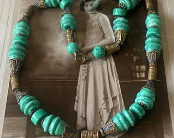 Könnte beinhalten: Eine vintage grüne und goldene Halskette mit großen, runden und facettierten Perlen. Die Halskette ist aus Glas und Metall und hat ein dekoratives Design.